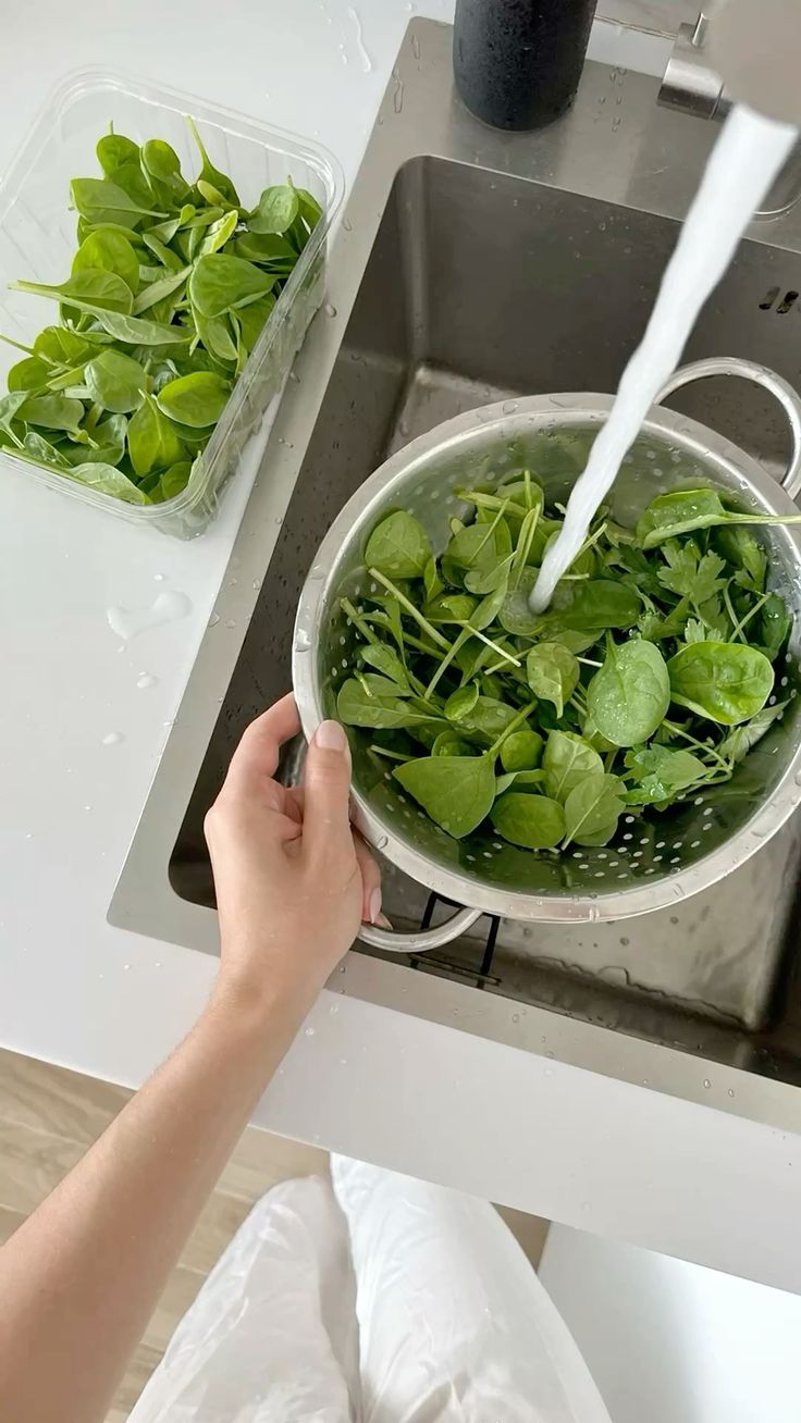 Mãos lavando vegetais na cozinha de casa